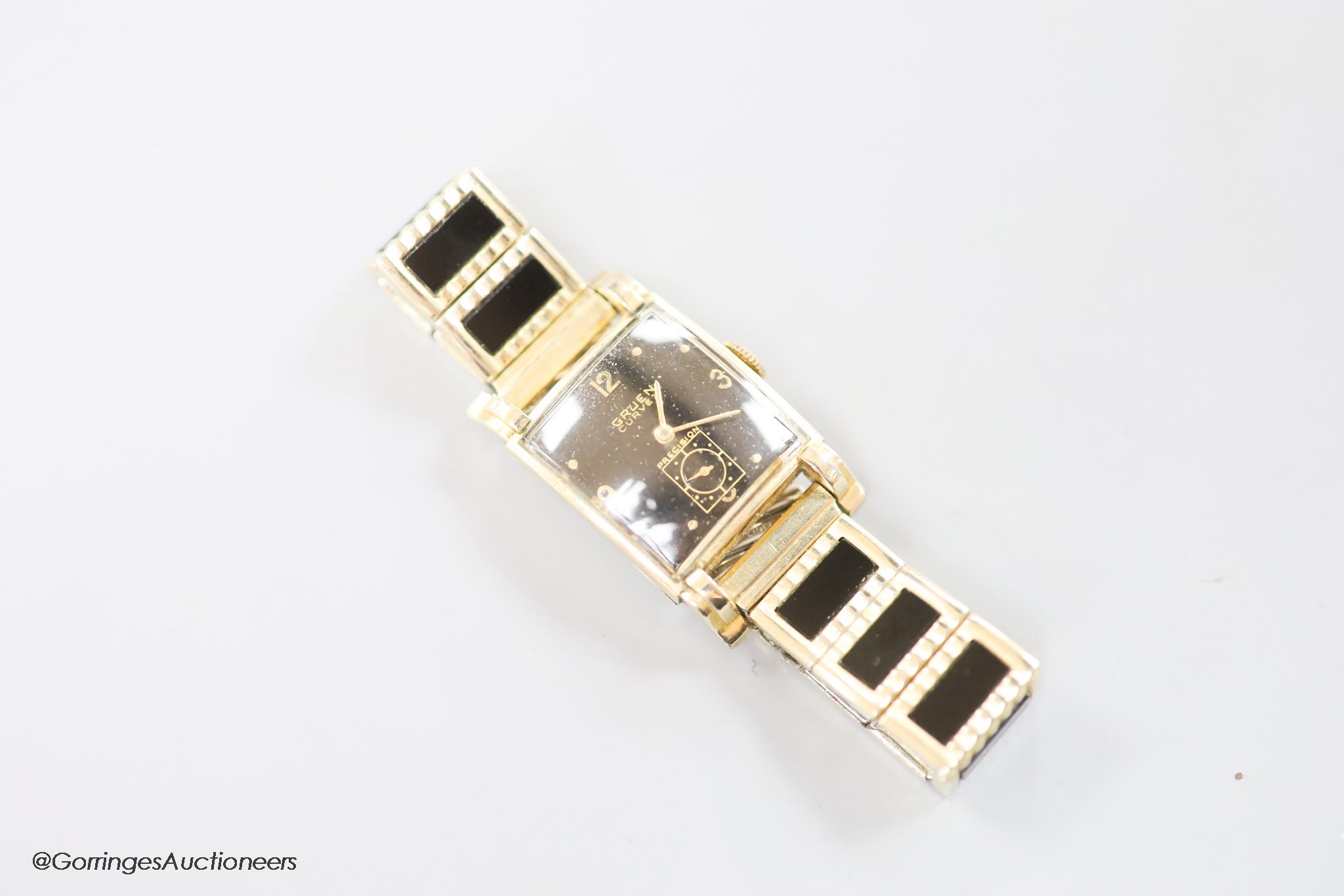 A gentleman's 1930's 10k gold filled, stainless steel Gruen Curvex Precision manual wind rectangular black dial wrist watch, on a gold plated and ceramic bracelet.